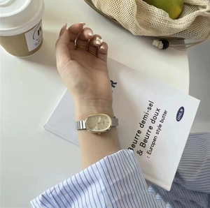 Detail shot of a stylish oval quartz watch with dual-tone steel band on a model wrist
