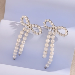 Detail view of butterfly pearl tassel earrings with silver base on a soft purple background