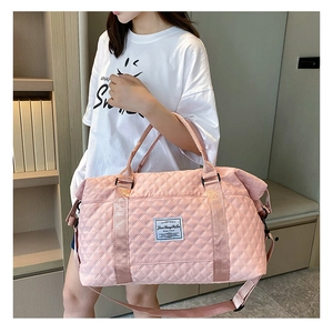 Pink quilted travel bag featuring nylon fabric and detachable shoulder strap on a model
