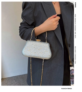 Detail of silver sequined evening clutch with gold metal handle and crown clasp