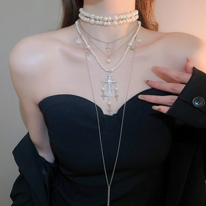 Detail of layered pearl necklace with diamond-set cross pendants and silver alloy chains