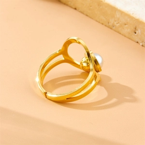 Elegant gold open ring with a single pearl accent on a minimalist stone display