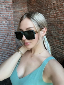 Detail of dark green marble frame sunglasses with gold metal temples on model