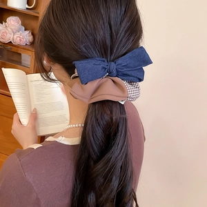 Blue denim bow and brown checkered scrunchie set on hair in a cozy interior