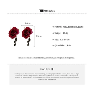 Macro shot of dark red rose earrings with black bead tassels and size specifications