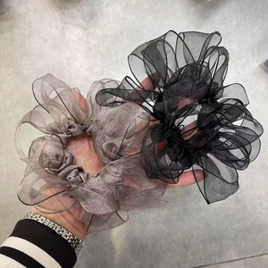 Elastici scrunchie in organza oversize nero e grigio con una texture brillante stratificata