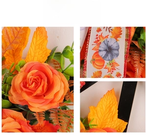 Detail of autumn wreath featuring orange silk roses, maple leaves and pumpkin print ribbon