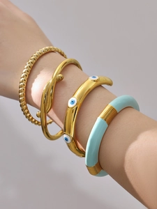 Dettaglio del set di quattro bracciali rigidi dorati con occhio del male in smalto blu