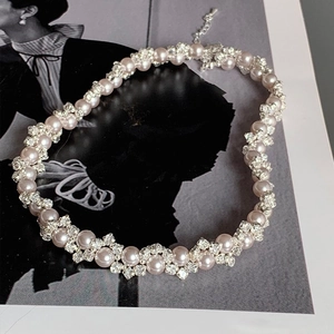 Elegant pearl and rhinestone floral choker necklace on a vintage magazine background