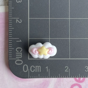 Mini resin white cloud charm with yellow star and pink swirl detail on measuring mat