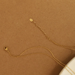 Macro detail of the 18K gold plated stainless steel O-chain with lobster clasp and tag