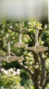 Detail eines handgefertigten Holzfisch-Windspiels mit Kupferglocken und Baumwollseilen