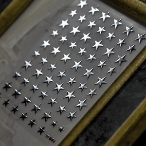 Macro shot of silver 3D star nail art stickers on a white card numbered to 841