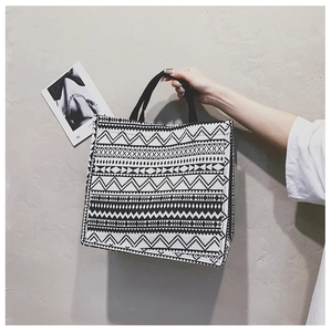 Detail of a minimalist black and white geometric canvas tote bag with woven handles