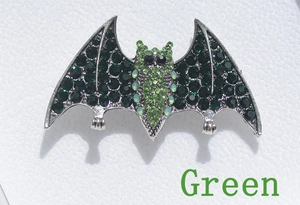 Macro shot of gothic bat brooch with green rhinestones on textured leather