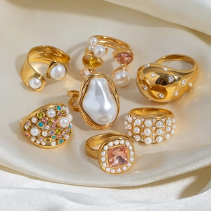 Gold stainless steel rings set with pearls and colorful zircons on silk background