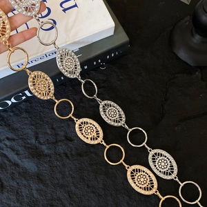 Detail of vintage gold and silver metal waist chains with embedded pearls on a magazine