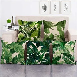 Set of five linen pillow covers with tropical green leaf patterns on a beige sofa