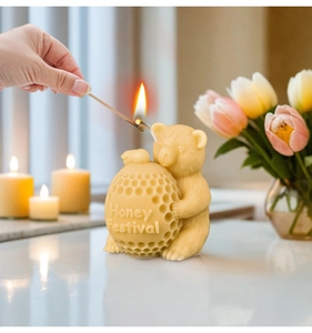 Nahaufnahme einer Bären-Wabenkerze beim Anzünden mit Honey Festival Schriftzug
