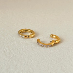 Macro view of gold-plated C-shaped ear cuff featuring pave-set cubic zirconia stones