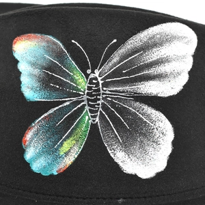 Detail shot of the vibrant hand-painted butterfly print on a black felt fedora hat