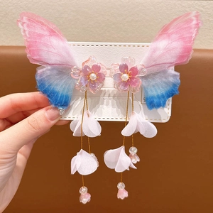 Detailed close-up of butterfly hair clips with blue gradient wings and floral tassels