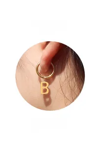Gros plan d'une boucle d'oreille dorée avec pendentif lettre B sur un mannequin