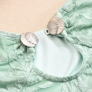 Close-up of mint green lace fabric with silver shell-shaped metal buckle detail