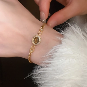 Gros plan du bracelet doré vintage avec pierre marron et pavé de diamants au poignet