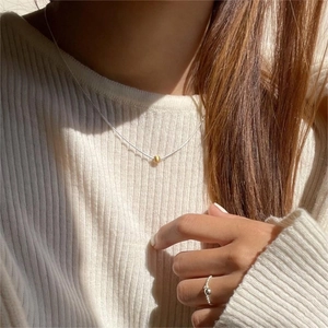 Detailed close-up of a mixed gold bead silver chain necklace and beaded silver ring