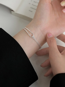 Detail of minimalist 925 silver double chain bracelet with knot element on woman wrist