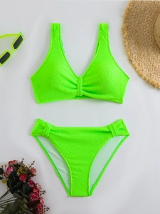 Detailed flat lay of a neon green textured bikini set with beach vacation accessories