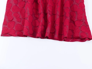 Vue détaillée du tissu jacquard rouge avec des motifs élégants de roses en 3D