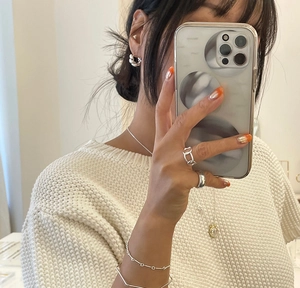 Detailed look at twisted rope earrings and stacked silver jewelry on a model