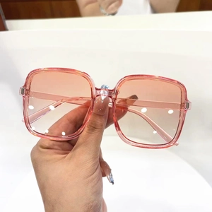 Detail of square oversized sunglasses with pink-orange gradient lenses and clear frames