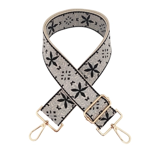 Detail showing thick jacquard shoulder strap with black embroidery and gold metal hooks