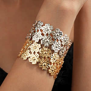 Close-up of wide cuff bracelet featuring two-tone metal floral hollow design