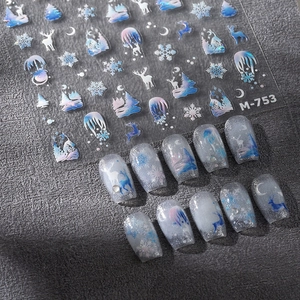 Christmas nail stickers with holographic reindeer and snowflake designs on blue glitter nails
