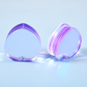 Macro detail of heart-shaped glass ear gauges with rainbow purple iridescent finish