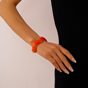 Close-up of vibrant orange wavy acrylic resin bangle on a woman's wrist