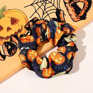 Detail of Halloween scrunchie with pumpkin prints and Happy Halloween text on satin fabric