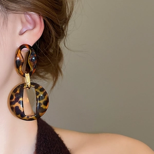 Close-up of leopard print acrylic geometric drop earrings with gold metal accents