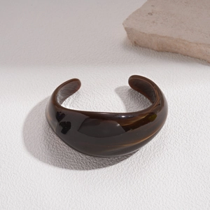Detailed view of translucent brown acrylic open bangle with amber texture and smooth finish