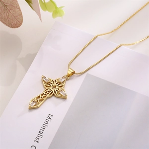 Macro shot of gold cross pendant with cubic zirconia on minimalist white card background