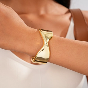 Close-up of a wide polished gold twisted cuff bracelet on a woman's wrist