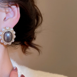 Close-up of vintage oval dark grey pearl earring with gold trim worn on model ear