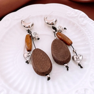 Detail of vintage ethnic earrings with wooden beads and a heart-shaped love pendant