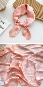 Detail of pink silk scarf showing premium paisley patterns and satin texture quality