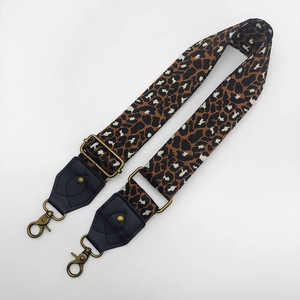 Detail of leopard print wide fabric bag strap with leather ends and metal hooks