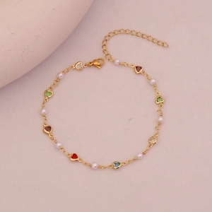 Detail of gold chain anklet featuring colorful heart crystals and small white pearls
